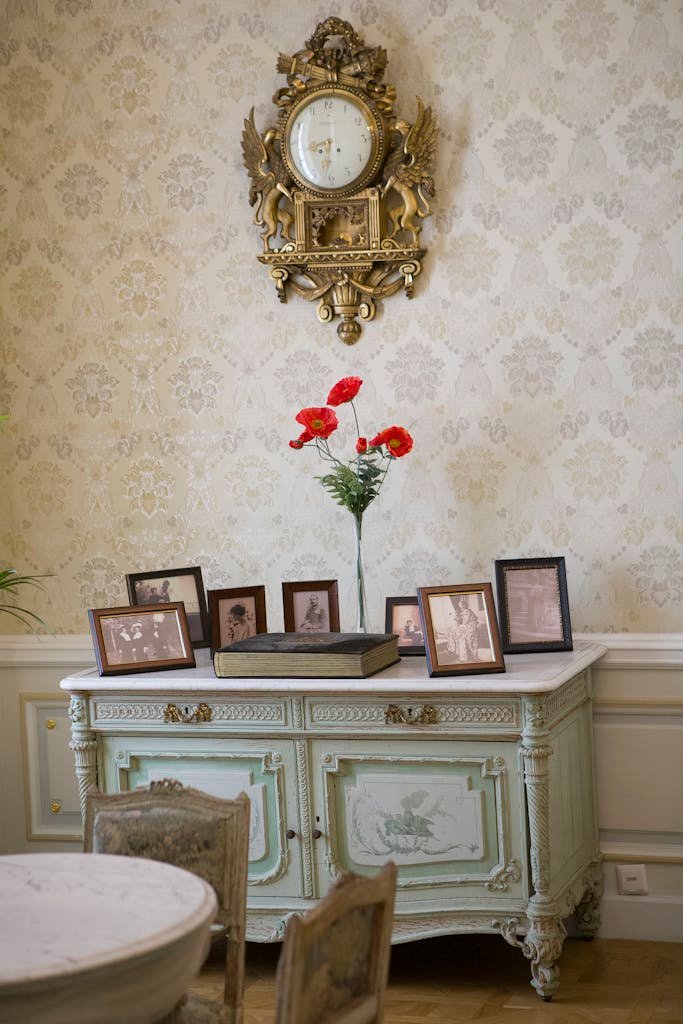 Elegant vintage interior with antique clock, decorated dresser, and framed photos.